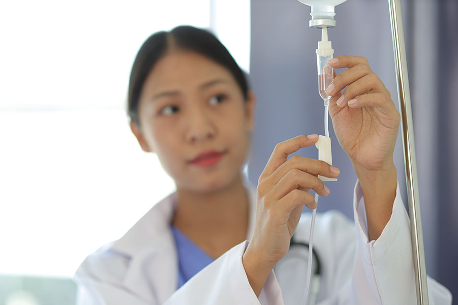 A clinician carefully adjusting an infusion line.