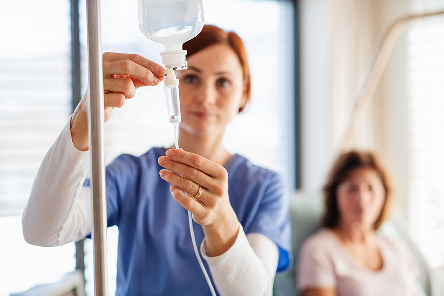 An Agile Infusion nurse preparing an IV drip while a patient rests comfortably in the background.