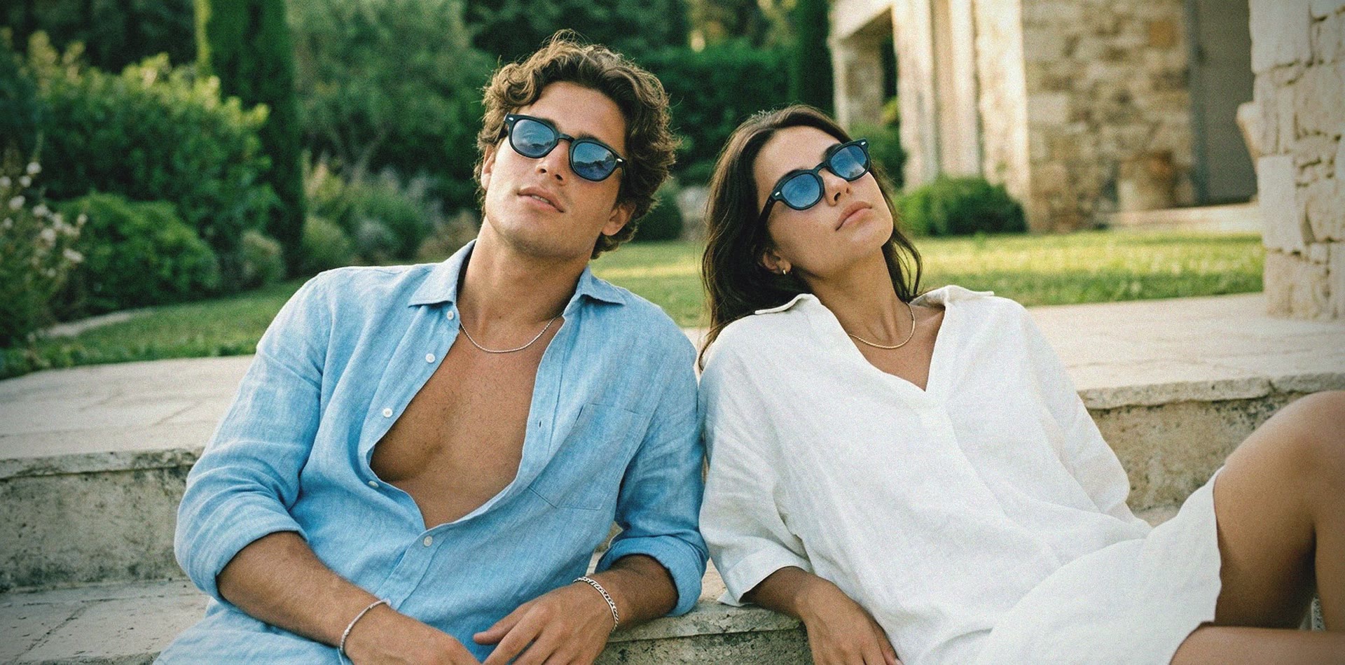 A couple wearing Aura Eyes blue-tinted round sunglasses in warm evening light