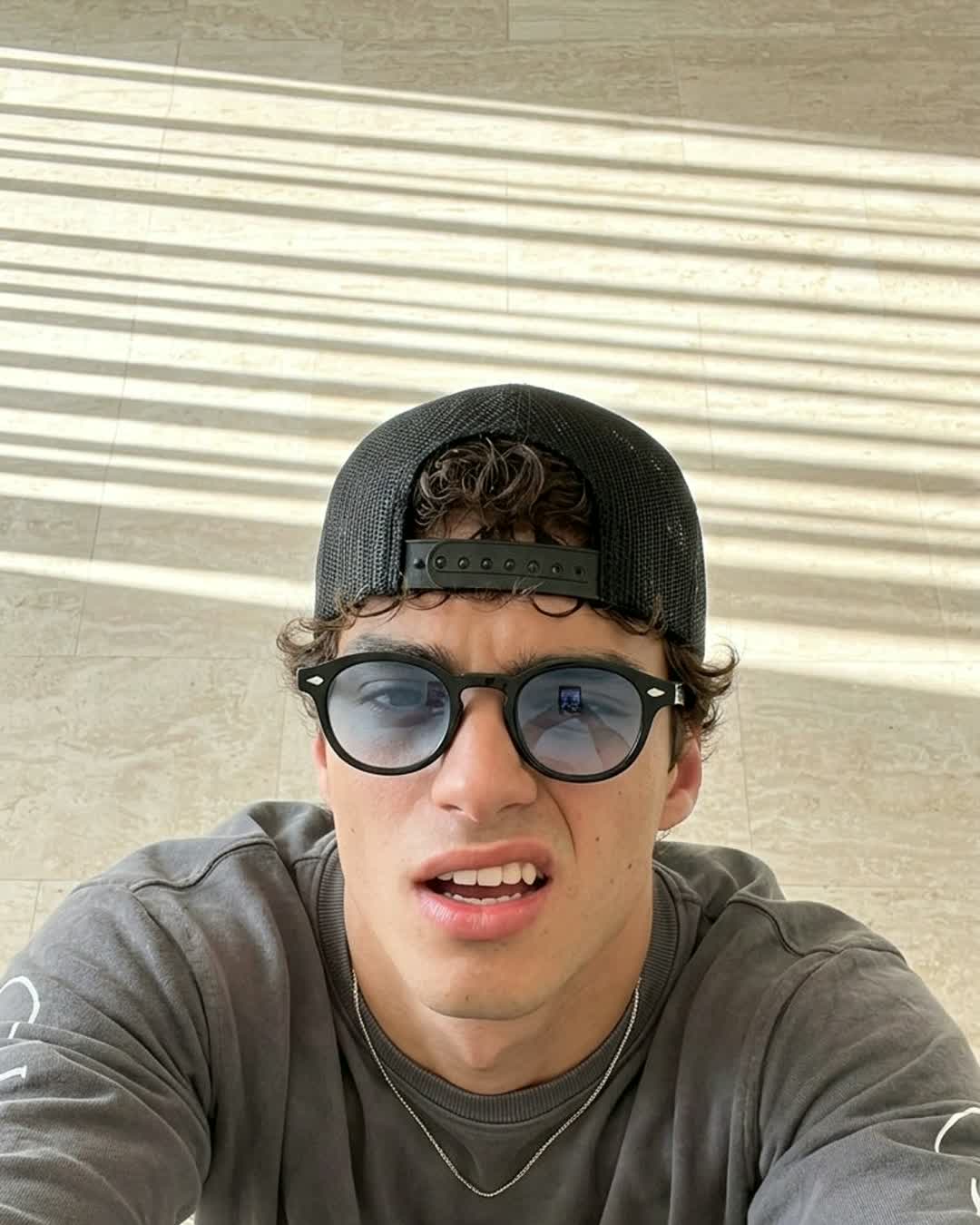 Man in a cap wearing Aura Eyes blue-tinted round sunglasses in the sun